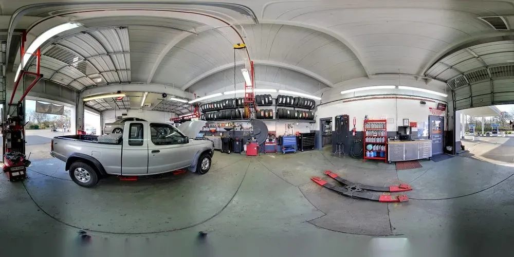 Wide view inside the repair shop at Thompson Lane Auto, with a pickup and tire racks