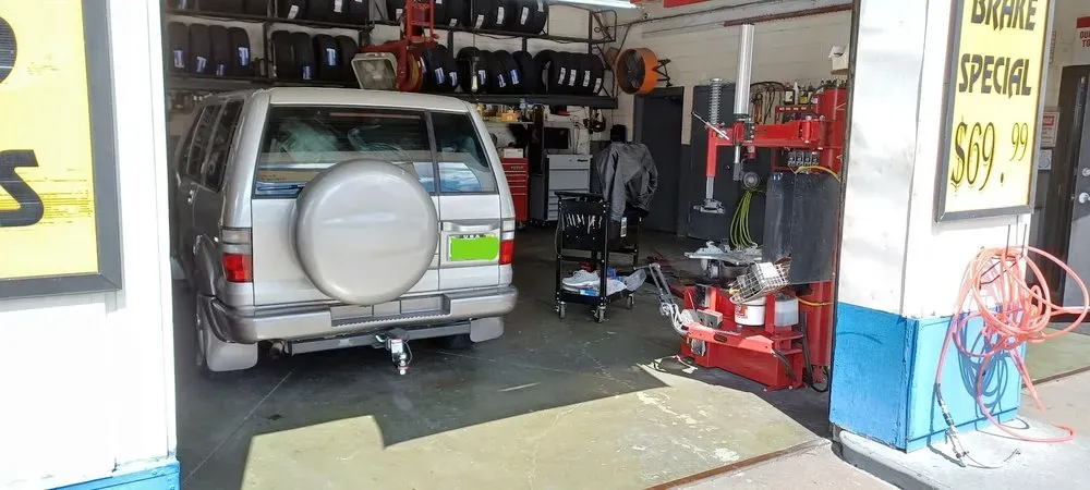 Silver SUV with a spare tire cover in the tire service bay at Thompson Lane Auto